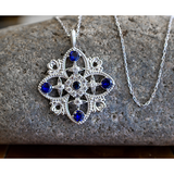 Antique Blue Sapphire September Birthstone Sterling Silver Cross Pendant - With 18" Sterling Silver Chain on a rock