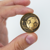 front of Soccer Team Antique Gold Plated Sports Coin in between fingers